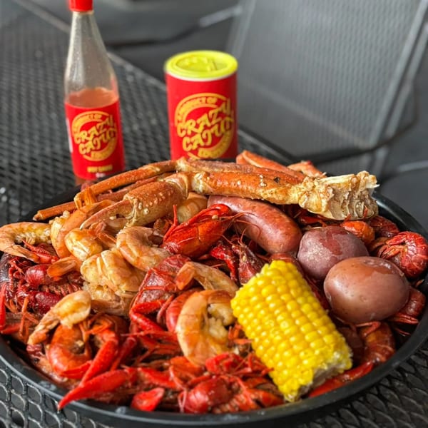 A seafood boil with crawfish, shrimp, crab legs, sausage, corn, and potatoes, with Crazy Cajun seasoning.